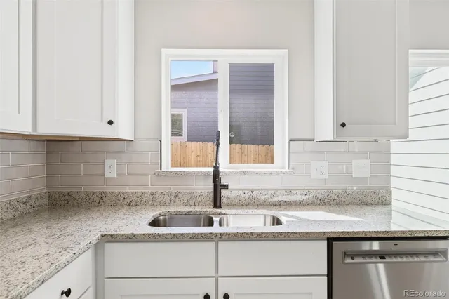 a kitchen with granite countertop white cabinets and a sink