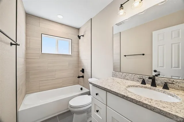a bathroom with a granite countertop sink toilet mirror and bathtub