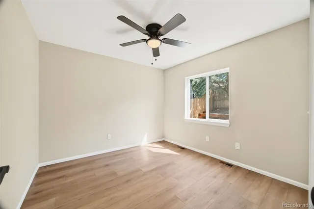 an empty room with wooden floor and ceiling fan