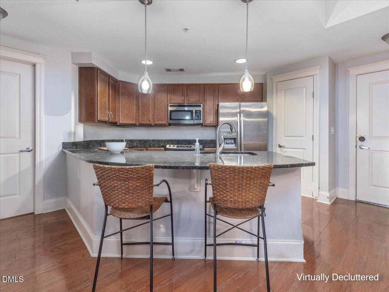 222 Glenwood Avenue, Unit 304 Raleigh, NC 27603 - Photo 13 of 23 a kitchen with stainless steel appliances granite countertop a sink a microwave refrigerator and chairs