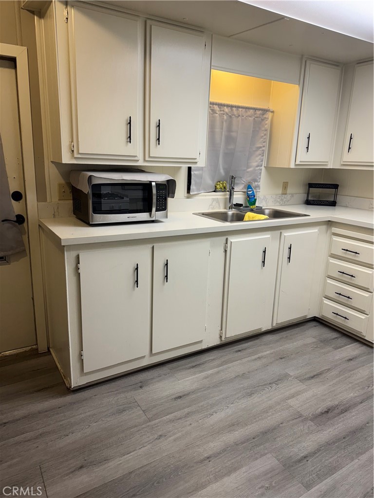 2751 Reche Canyon Road, Unit 185 Moreno Valley, CA 92555 - Photo 6 of 17 a kitchen with stainless steel appliances granite countertop a stove a sink and white cabinets with wooden floor
