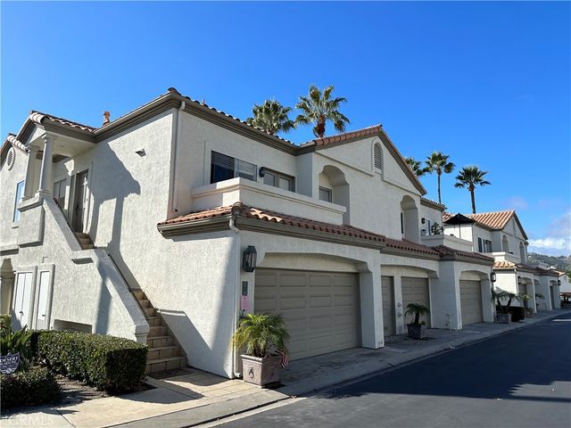 a view of a white house with a small yard and potted plants