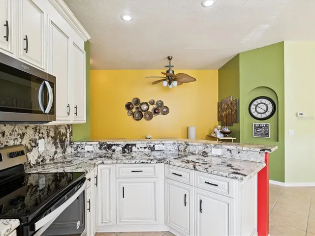 a kitchen with granite countertop white cabinets and stainless steel appliances