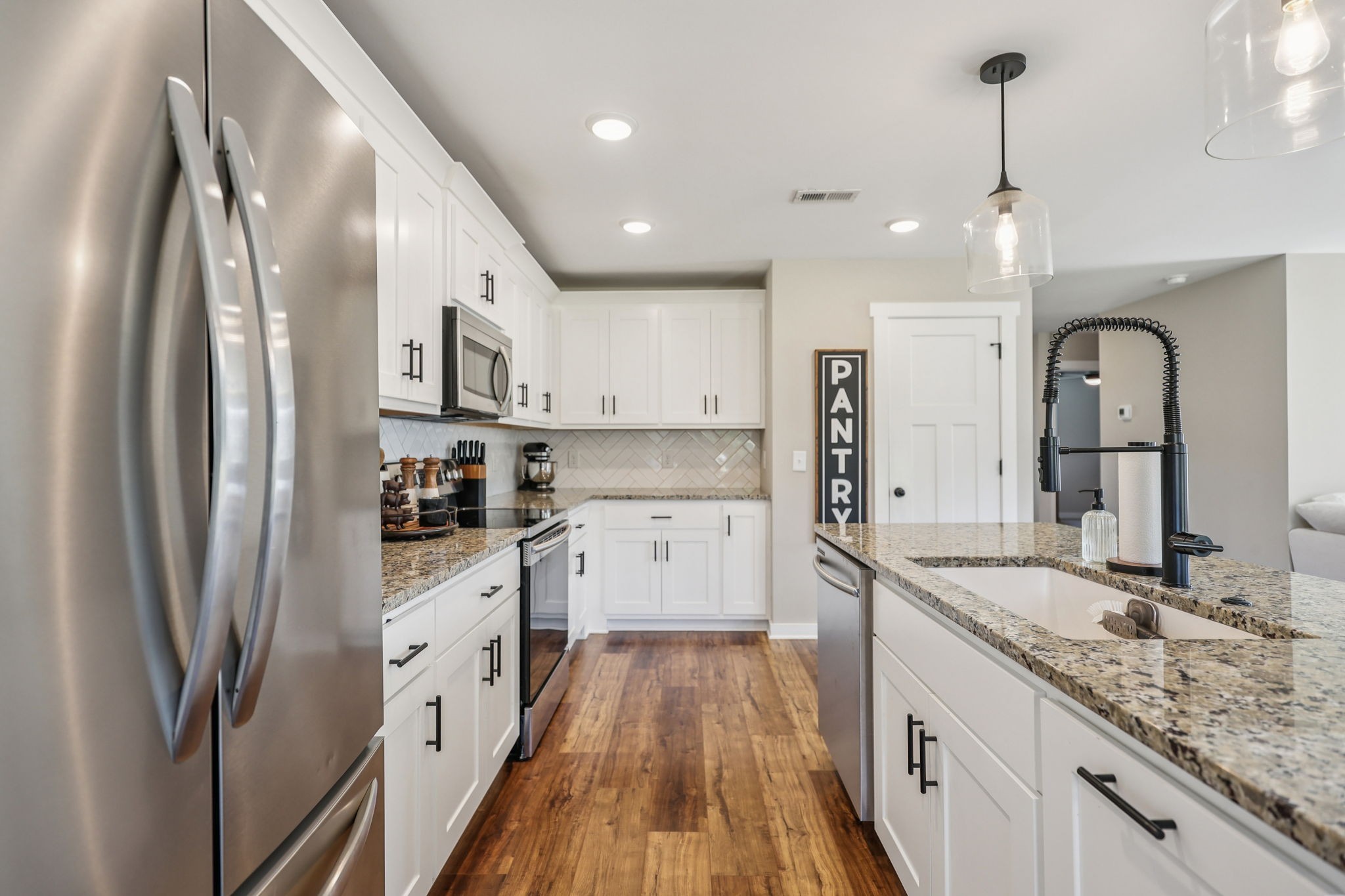 310 Skipping Stone Road Christiana, TN 37037 - Photo 9 of 50 a kitchen with stainless steel appliances granite countertop a refrigerator a sink dishwasher a stove and white cabinets with wooden floor