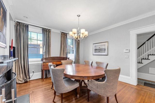 a dining room with wooden floor a chandelier a glass table and chairs