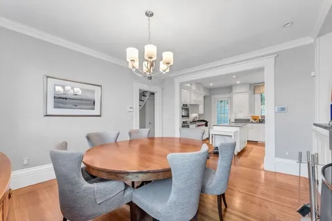 a dining room with wooden floor a chandelier a wooden table and chairs