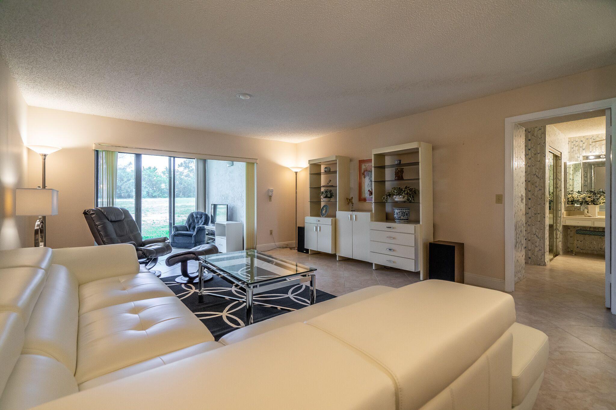 9276 Vista Del Lago, Unit E Boca Raton, FL 33428 - Photo 2 of 23 a living room with furniture a large window and dresser