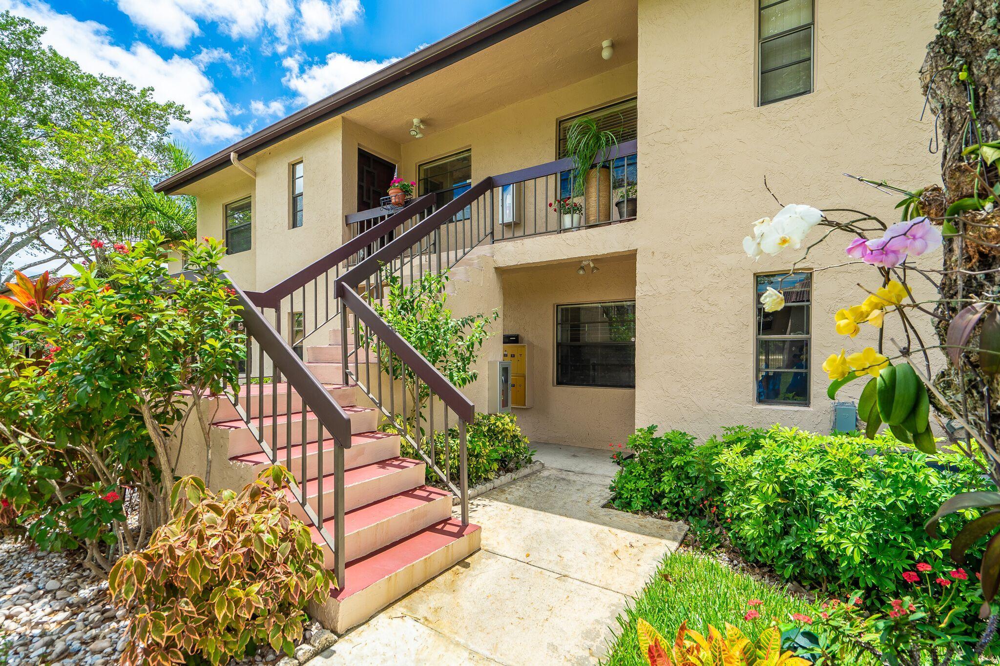 9276 Vista Del Lago, Unit E Boca Raton, FL 33428 - Photo 20 of 23 a view of a house with large windows and flower plants