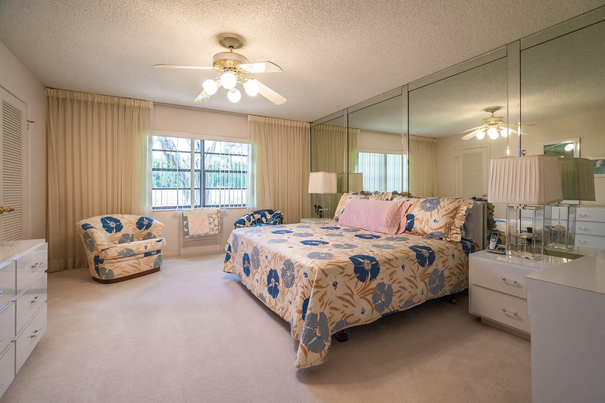 9276 Vista Del Lago, Unit E Boca Raton, FL 33428 - Photo 10 of 23 a spacious bedroom with a bed and a chandelier