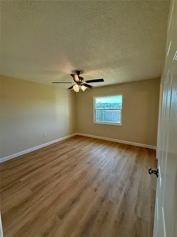 an empty room with wooden floor closet and windows