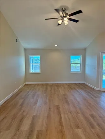 a view of empty room with wooden floor and fan