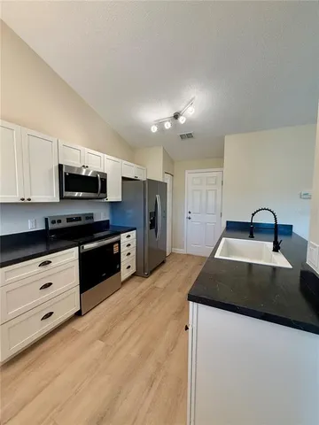 a kitchen with granite countertop a stove a sink and a microwave