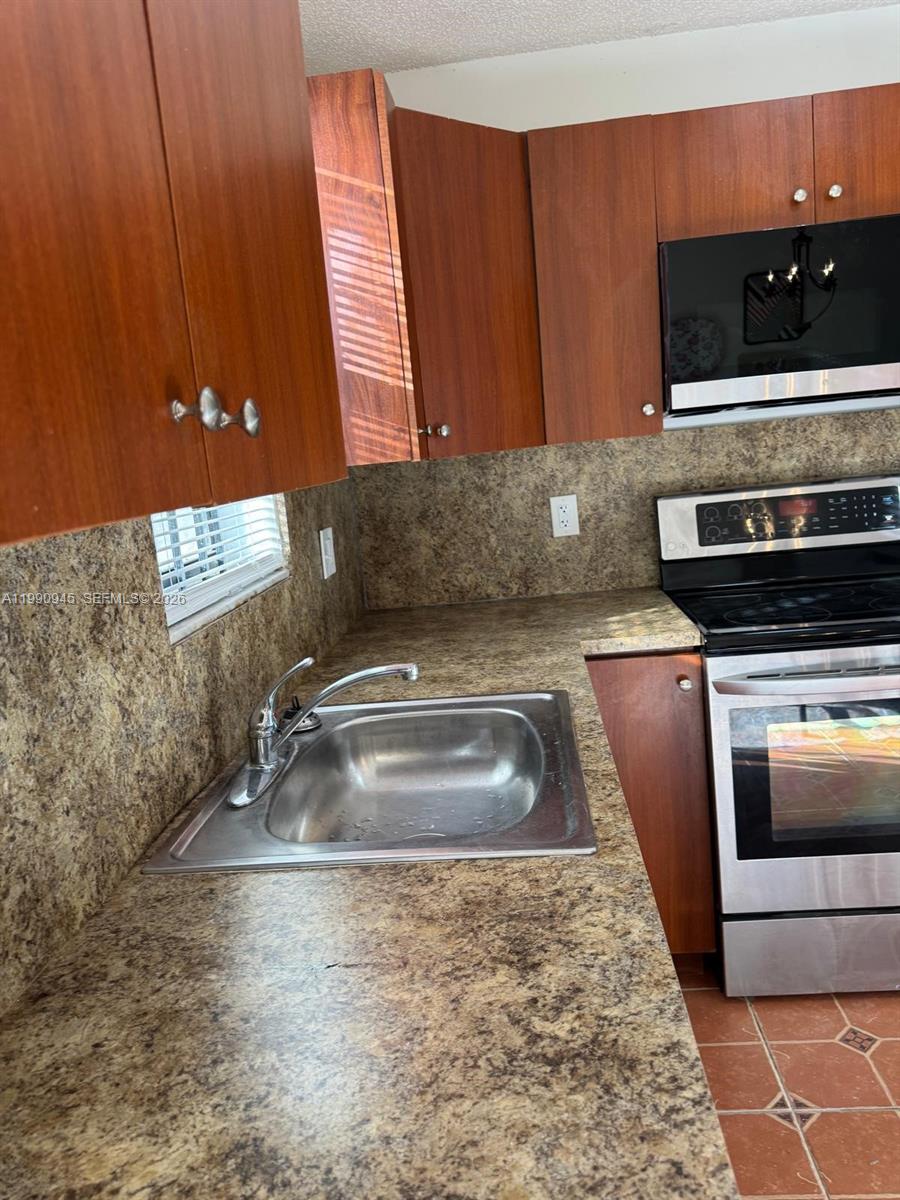 28002 Southwest 140th Court Homestead, FL 33033 - Photo 11 of 12 a kitchen with granite countertop a sink and a stove top oven