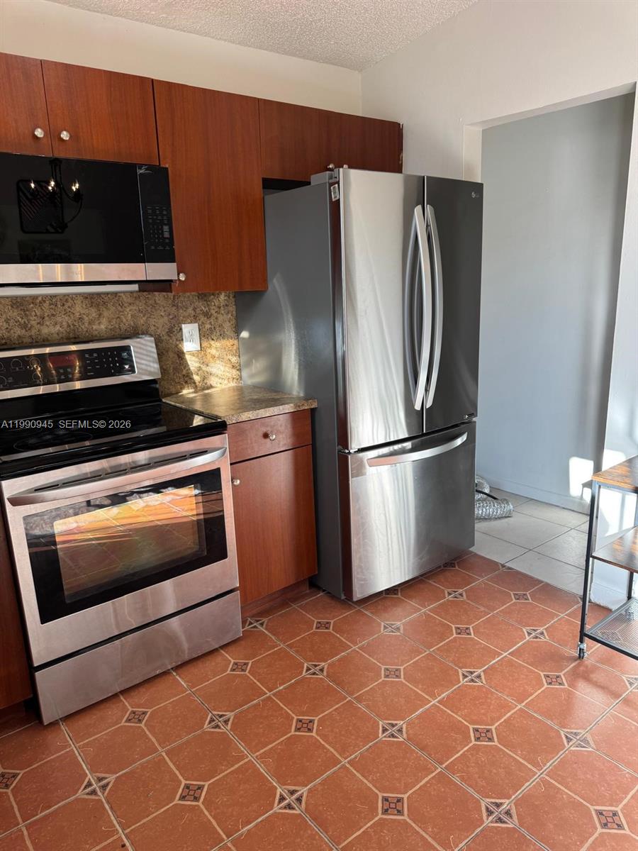 28002 Southwest 140th Court Homestead, FL 33033 - Photo 12 of 12 a kitchen with granite countertop a refrigerator and a stove top oven