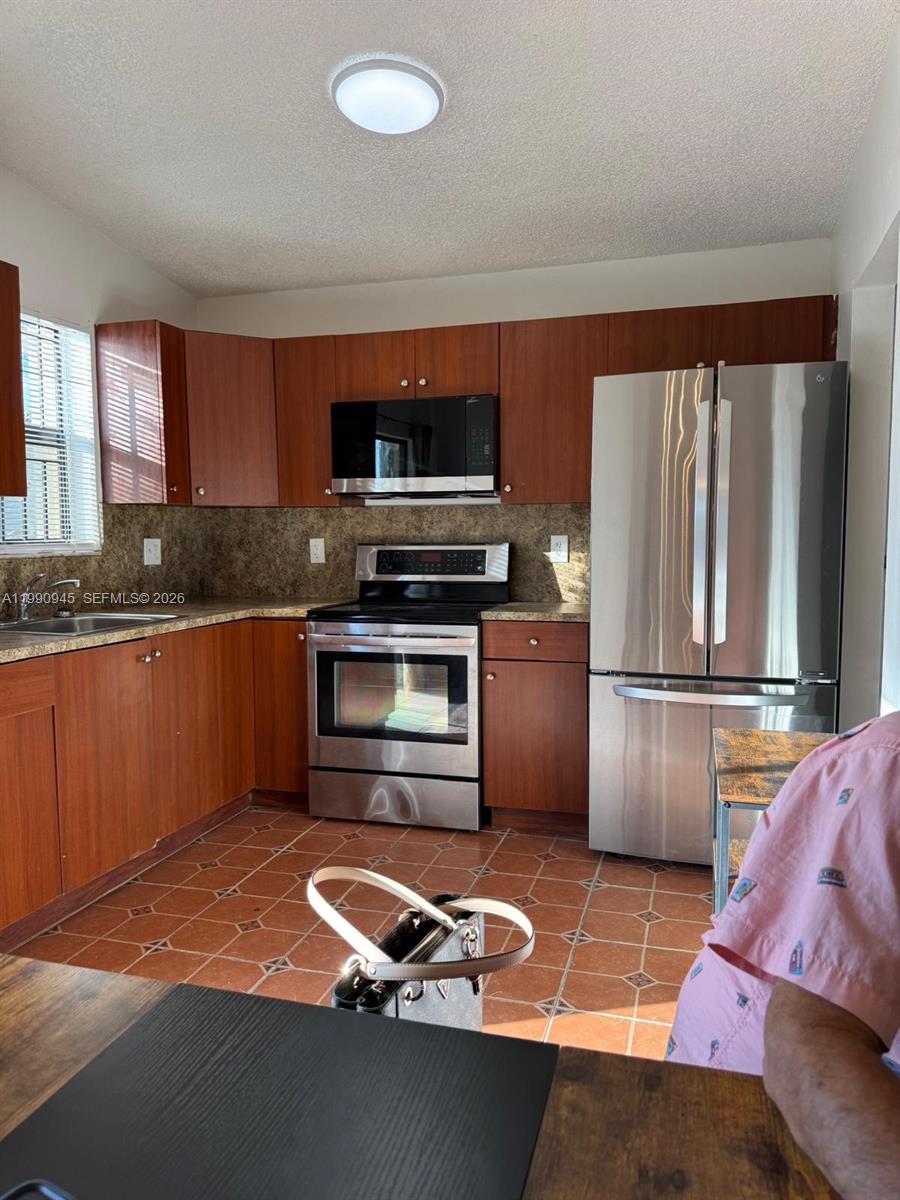 28002 Southwest 140th Court Homestead, FL 33033 - Photo 9 of 12 a kitchen with stainless steel appliances kitchen island granite countertop a refrigerator stove and sink