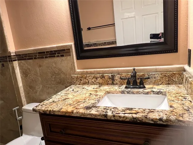 a bathroom with a granite countertop sink and a mirror