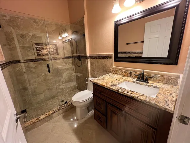 a bathroom with a granite countertop sink a toilet and a mirror
