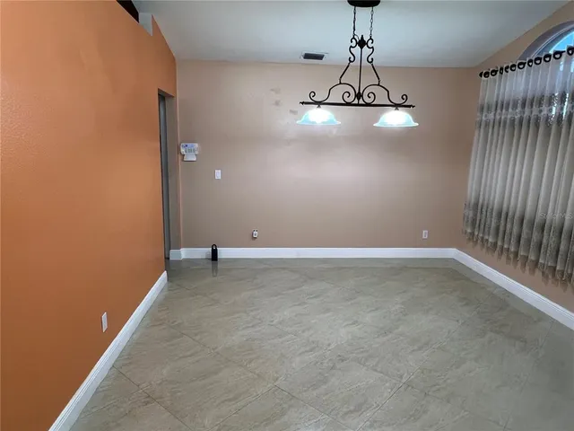 a view of a room with a hanging light and hardwood floor