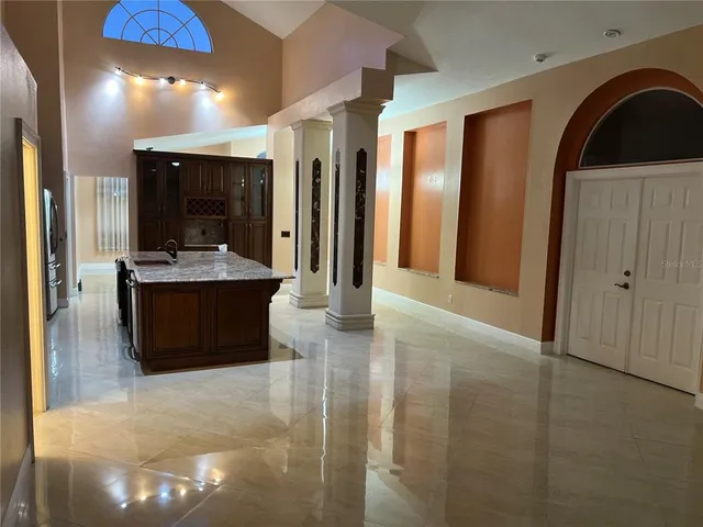 a living room with stainless steel appliances kitchen island granite countertop a refrigerator a sink and a stove