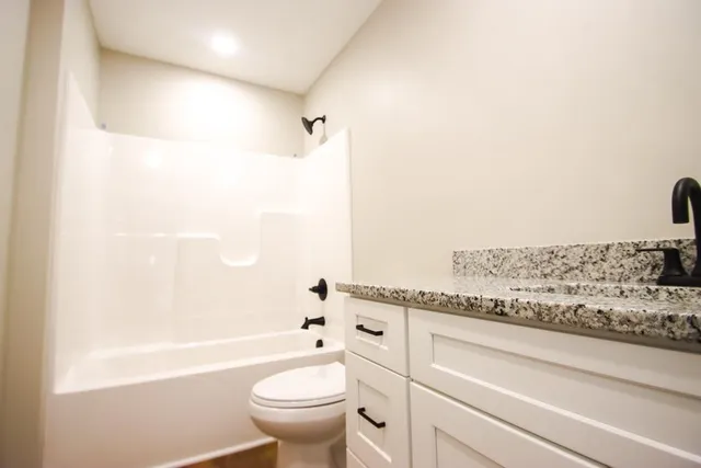 a bathroom with a granite countertop bathtub toilet and sink
