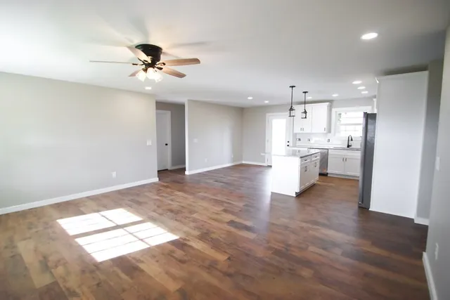 a view of a kitchen with a stove cabinets a ceiling fan and wooden floor