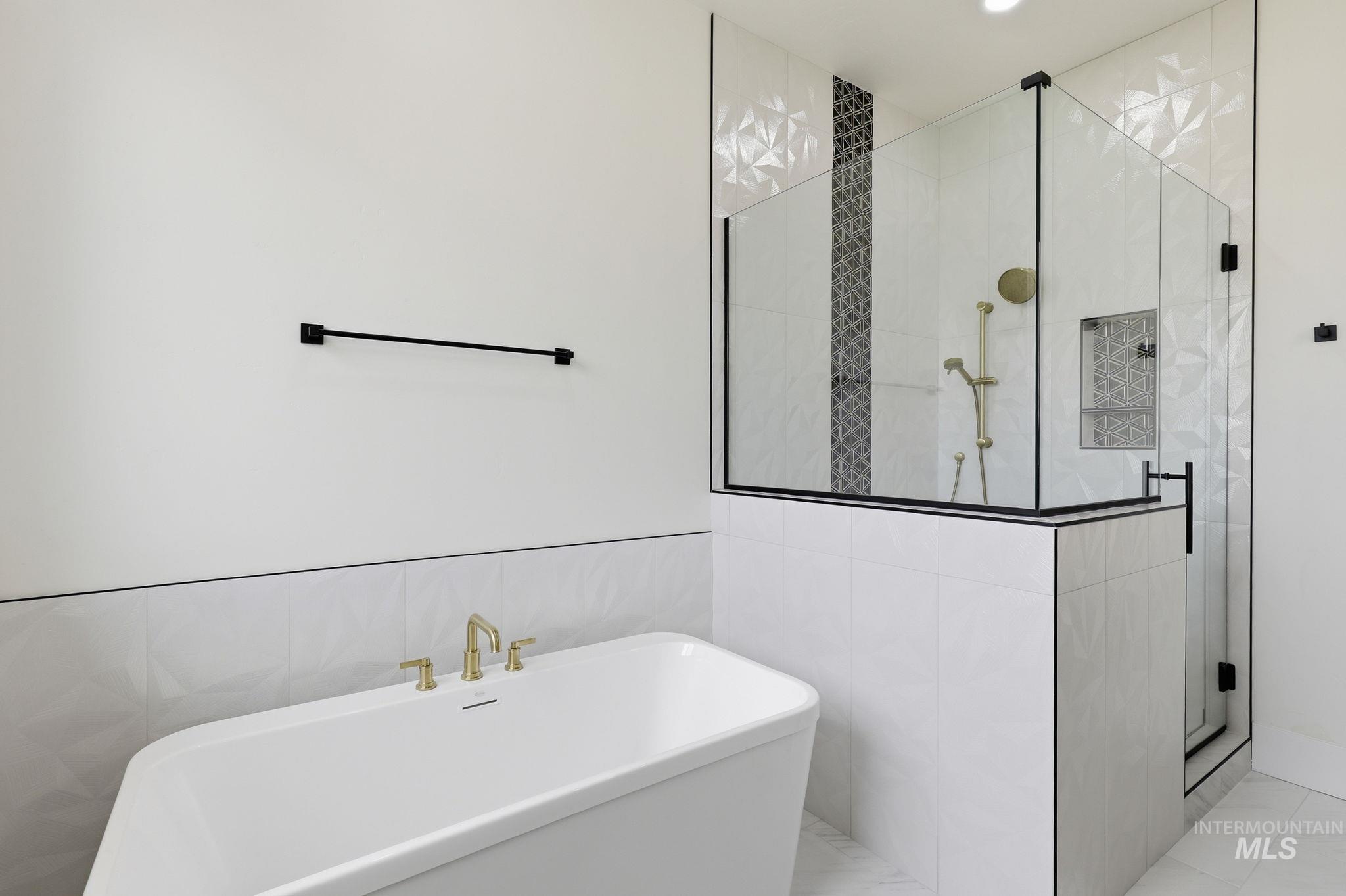 2321 Lower Bluff Road Emmett, ID 83617 - Photo 16 of 31 Freestanding soaking tub with gold-finish fixtures and a spacious glass-enclosed shower featuring a geometric tile accent wall and built-in niche
