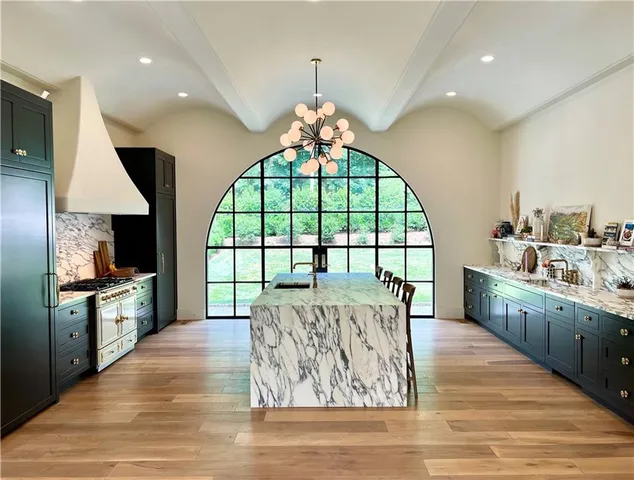 a large kitchen with kitchen island granite countertop a stove a sink and a large refrigerator