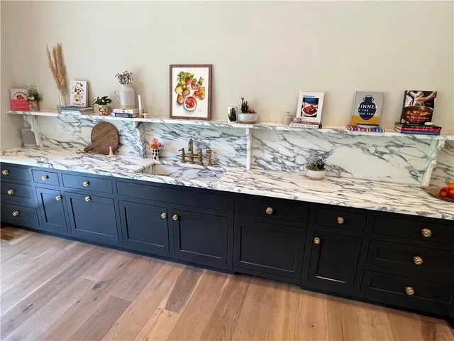 a spacious bathroom with a granite countertop sink and a wooden floor