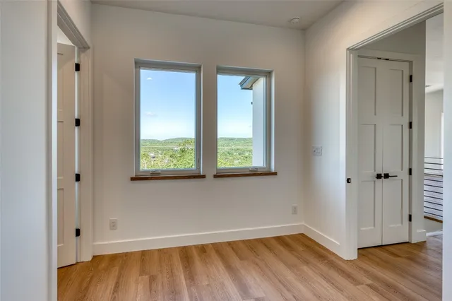 a view of an empty room with wooden floor and a window