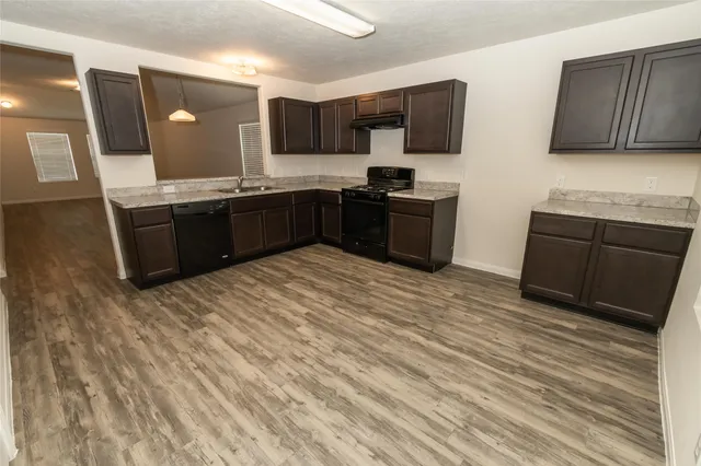 a kitchen with granite countertop a refrigerator and cabinets