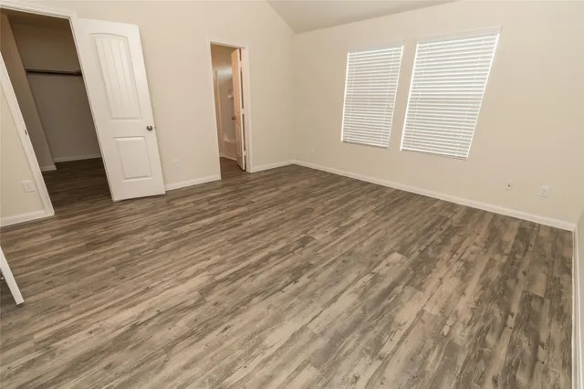 an empty room with wooden floor and window