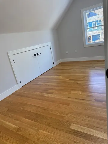 a view of empty room with window and wooden floor