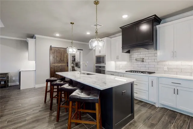 a kitchen with a sink a center island stainless steel appliances and cabinets