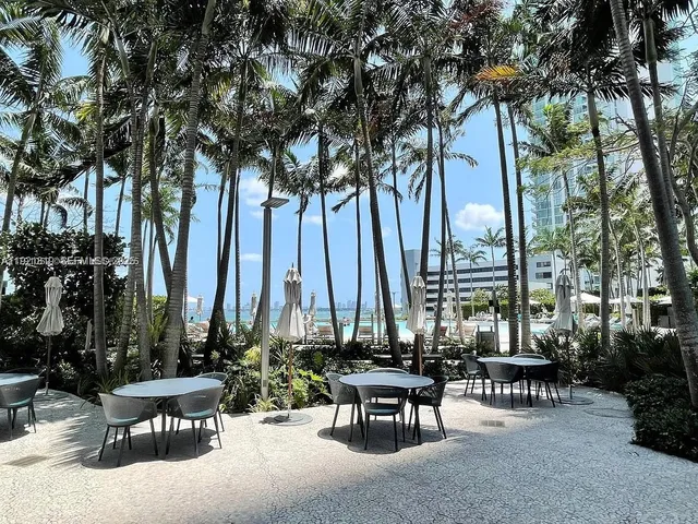 a view of a patio with table and chairs potted plants with floor to ceiling window