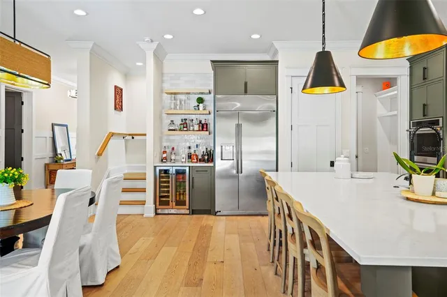 a kitchen view with stainless steel appliances kitchen island granite countertop a table chairs in it and wooden floors