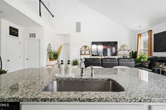 a kitchen with a stove a faucet and a flat screen tv