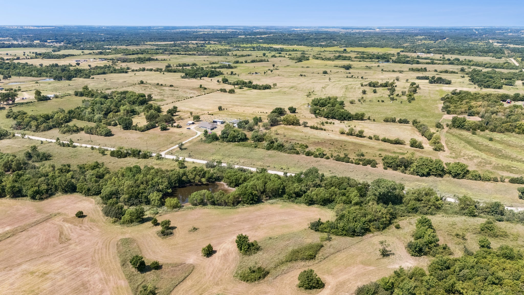 49301 South 360 Road Pawnee, OK 74058 - Photo 38 of 44 Expansive rural landscape featuring a single-story residence, a private pond, mature trees, and agricultural fields