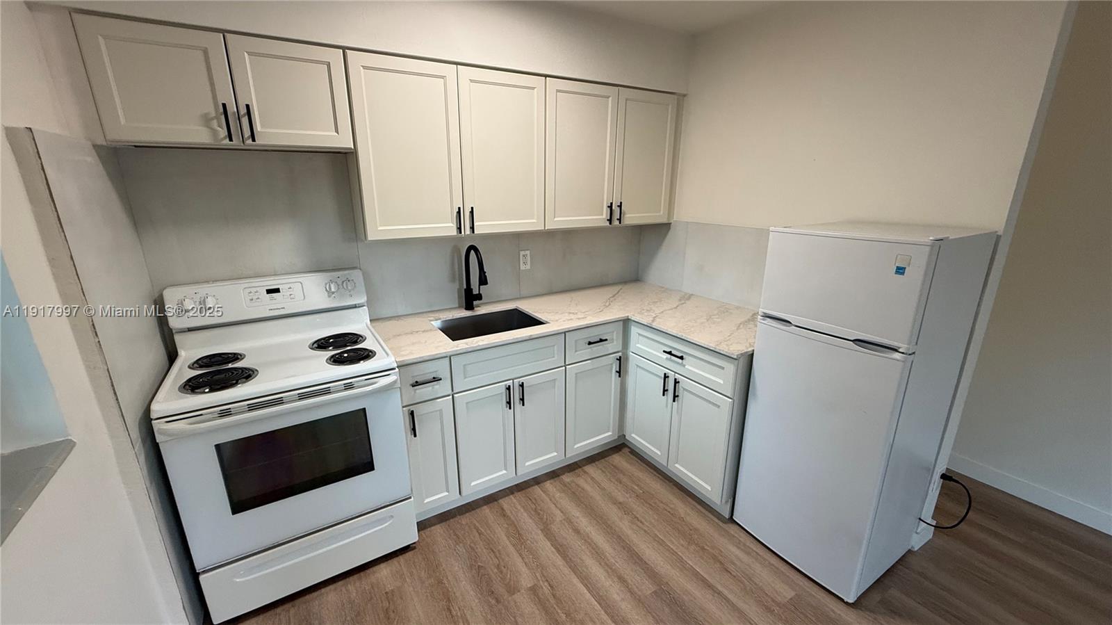 212 Southwest 13th Street, Unit 3 Dania Beach, FL 33004 - Photo 1 of 11 a kitchen with white cabinets and white appliances