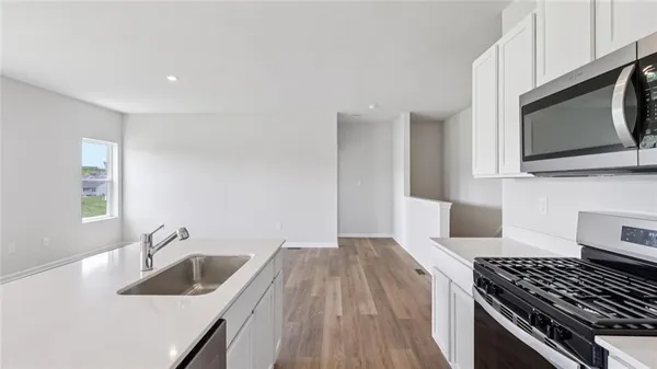 a kitchen with granite countertop a sink stainless steel appliances and cabinets