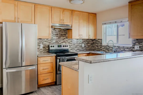 a kitchen with stainless steel appliances granite countertop a refrigerator a stove and a sink
