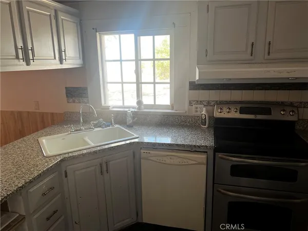 a kitchen with kitchen island granite countertop a stove top oven a sink a counter space and cabinets