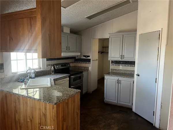 a kitchen with granite countertop white cabinets and white appliances