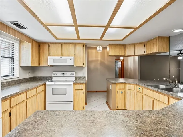 a kitchen with stainless steel appliances granite countertop a sink a stove a refrigerator with white cabinets and wooden floor