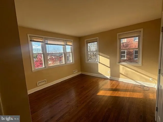 a view of an empty room with a window and wooden floor