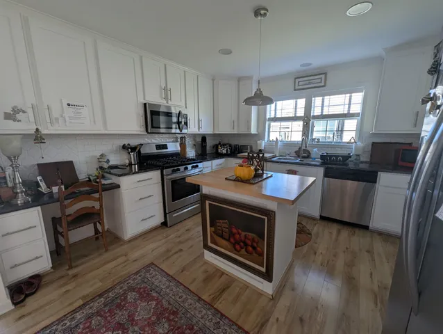 a living room with stainless steel appliances a stove a sink a refrigerator cabinets and a center island