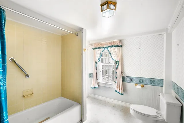a bathroom with a tub shower and toilet