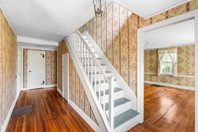 a view of a hallway with wooden floor staircase and front door