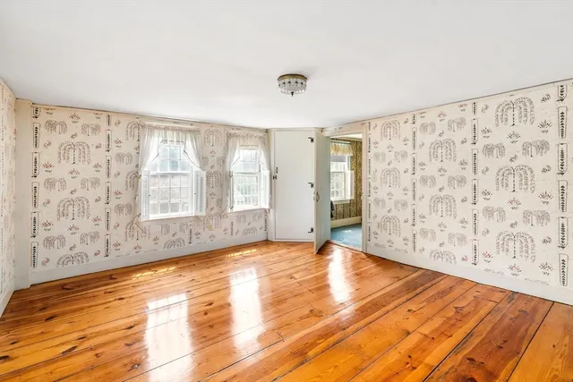 a view of an empty room with a window and wooden floor