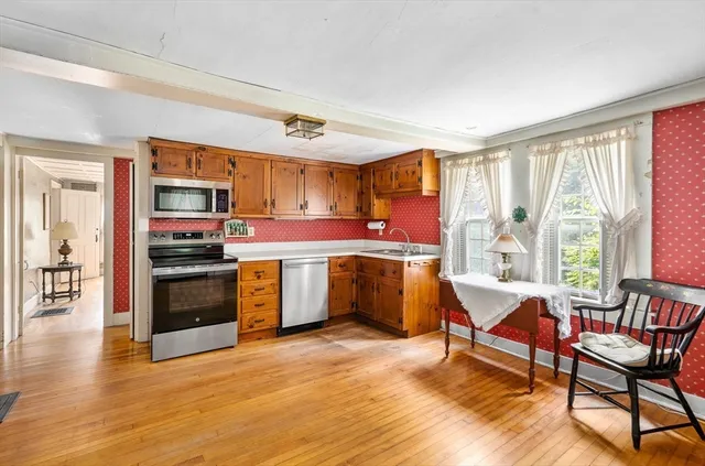 a kitchen with stainless steel appliances kitchen island granite countertop a stove top oven a sink dishwasher a dining table and chairs with wooden floor
