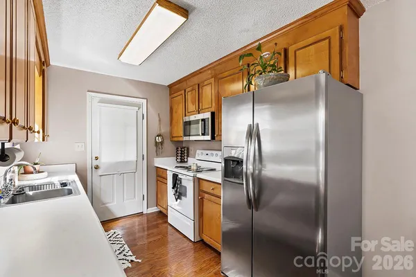 a kitchen with stainless steel appliances granite countertop a refrigerator a stove and a sink with wooden floor